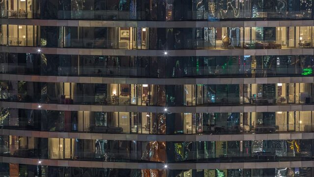 Outside view of windows in apartments of a high class building at night timelapse. Glowing yellow lights in skyscraper