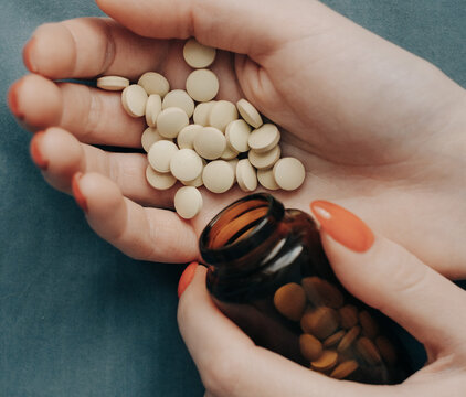 Close-up of pills in women's hands with a red manicure. Depression or mental health problems.