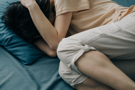 The young woman in bed hugged her head. Depression or mental health problems.