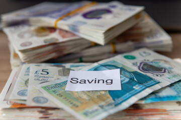 A pile bank notes with the word saving. Saving money, wealth concept.