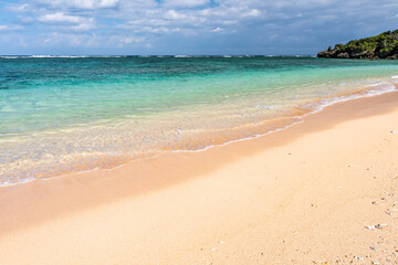 Fototapeta na wymiar Gentle turquoise sea wave on clear sand beach