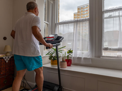 A Senior Man Trying To Keep Fit Working Out On A Treadmill At Home.