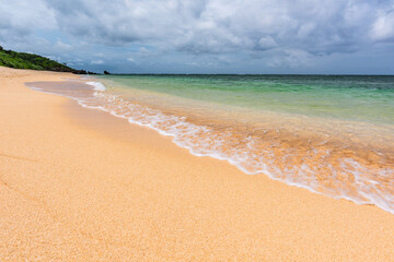 Soft aqua green sea wave over clear sands on a paradise beach.