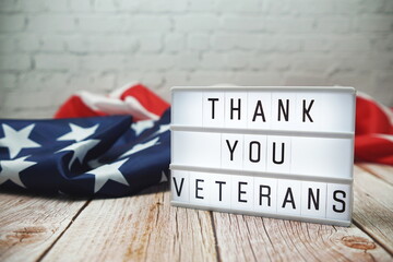 Thank You Veterans word in lightbox and American flag on wooden background