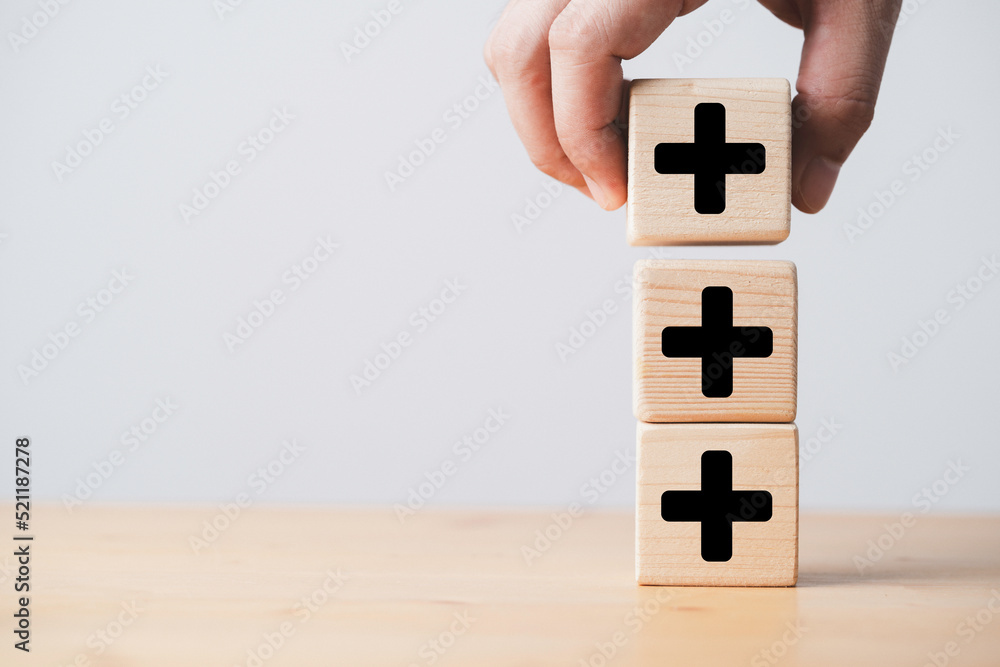 Poster hand stacking plus sign which print screen on wooden cube block for addition and positive mindset th
