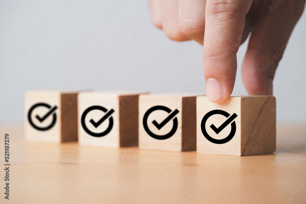 Poster hand putting correct sign which print screen on wooden cube block for approve project and iso docume