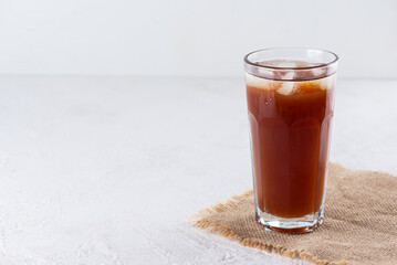 Kvass with ice in a glass on a light background. Horizontal orientation, copy space.