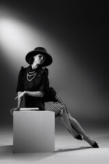 Portrait of beautiful woman in image of famous fashion designer posing in stylish classical outfit. Black and white photography. Grace and elegance