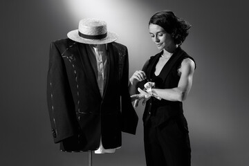Portrait of beautiful woman in image of famous fashion designer working on male classic suit. Black and white photography. Costume designer