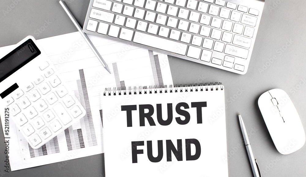 Poster trust fund text written on notebook on grey background with chart and keyboard , business concept