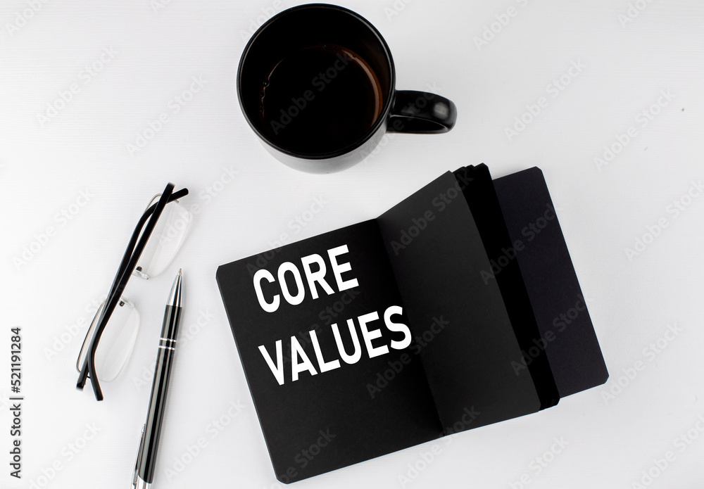 Poster core values written text in small black notebook with coffee , pen and glasess on white background. 