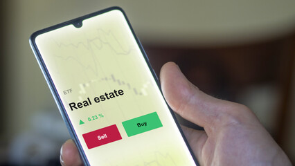 An investor's analyzing the real estate etf fund on a screen. A phone shows the prices of building construction.