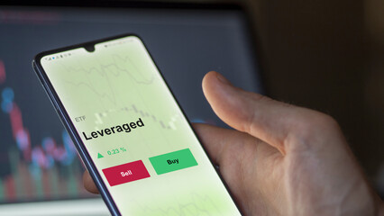 An investor's analyzing the leveraged etf fund on a screen. A phone shows the prices of leverage ETF.