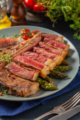 Grilled, medium-baked t-bone beef steak. Served with asparagus.