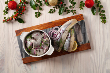 Herring fillets in oil. Served with onion in a bowl. Wooden background.