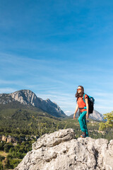 Naklejka premium A young woman climbed to the top of the mountain and looks at the valley