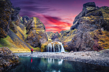 Amazing Icelandic Landscape. Photographer standing on canyon of river before majestic Stjornarfoss...