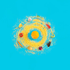 Raw vegetables revolve around boiled egg yolk with culinary condiment on bright blue background. Solar system represantation, healthy diet idea.
