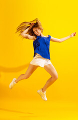 Fototapeta na wymiar Happy young girl, student jumping isolated on bright yellow background. Concept of beauty, art, fashion, emotions and facial expressions