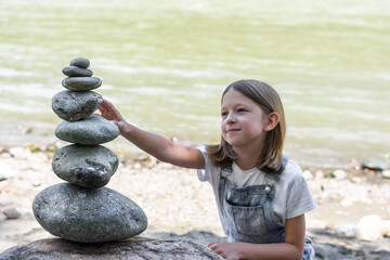 Child building a stone castle on the river. Meditation and relaxation therapy. Zen stone. Image...