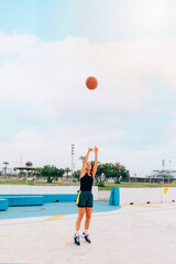 Athlete woman doing a basketball hoop shot on a street court. Lifestyle, sport and wellness