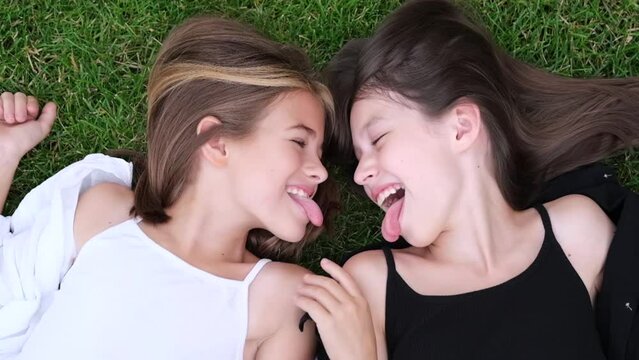 Outdoors closeup portrait of two adorable children share love and friendship. Two sisters having fun on sunlight and nature background. Happy family concept. Two girls twins in the park in summer.