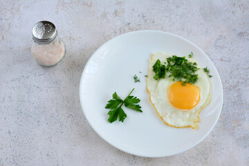 fried egg with yellow yolk and parsley isolated on white plate