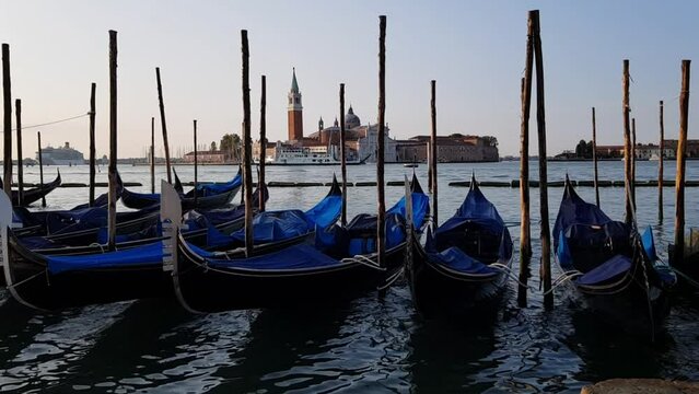 Gandolas sway on the waves in the canal of Venice. Moored tourist gondolas in Venice canal. Venice, Italy