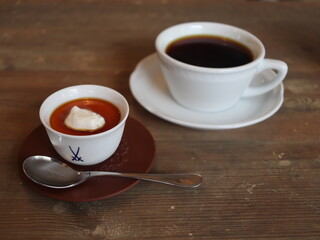 喫茶店の白いカップに入ったコーヒーとプリン