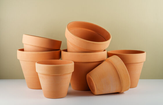 Many clay flower pots on white table and beige wall background 