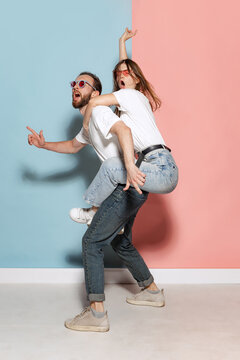 Young crazy man and astonished girl having fun isolated on blue and pink trendy color background. Emotions, youth, love and active lifestyle concept