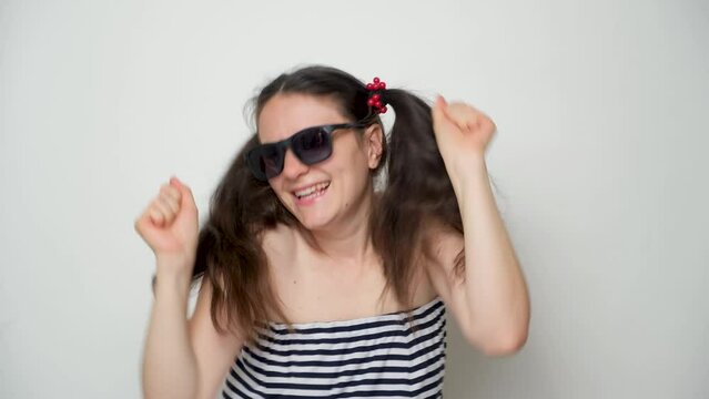 A funny woman in sunglasses dances and has fun, takes off her glasses and laughs