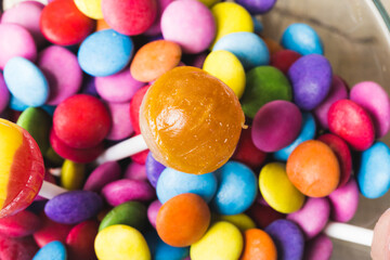 Close-up of lollipop with multi colored chocolate candies in bowl
