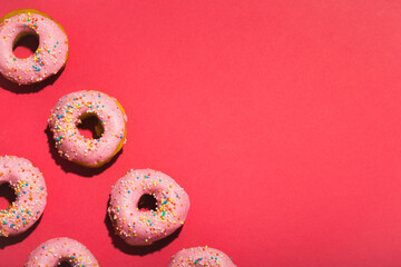 Overhead view of sprinklers on fresh donuts arranged by copy space on pink background - Powered by Adobe