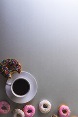 Obraz na płótnie Canvas Directly above view of fresh black coffee in cup amidst donuts by copy space on white background