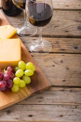 Tuinposter High angle view of cheese with grapes and red wine on table, copy space © wavebreak3