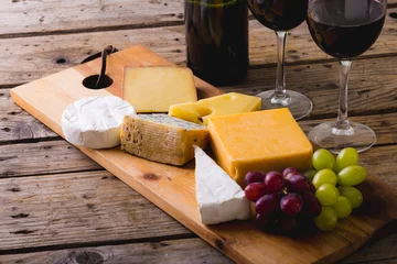  High angle view of various cheese with grapes and red wine on table, copy space © WavebreakMediaMicro