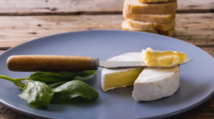 Foto op Canvas Close-up of brie cheese with herb and knife in plate on table, copy space © wavebreak3