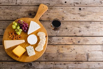 Rollo Directly above shot of various cheese with grapes and red wine on wooden table, copy space © WavebreakMediaMicro