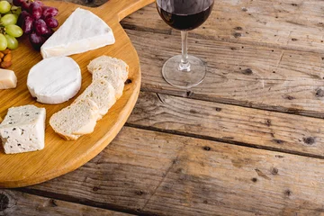 Foto op Plexiglas High angle view of various cheese with grapes and red wine on wooden table, copy space © wavebreak3
