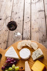 Foto op Plexiglas High angle view of red wine with various cheese and grapes on wooden table, copy space © WavebreakMediaMicro