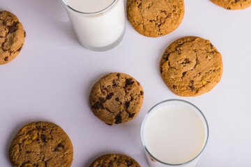 Overhead view of milk in glasses with cookies over white background, copy space