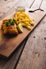 High angle view of french fries with seafood and sauce on wooden board, copy space