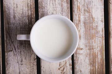 Fototapeta na wymiar Overhead view of milk in cup on wooden table, copy space