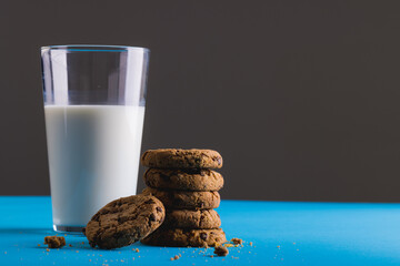 Close-up of milk glass by stacked cookies against gray background, copy space