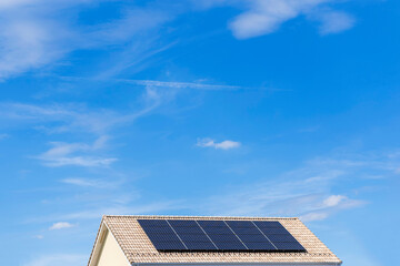 太陽光パネルが設置された住宅の屋根と快晴の青空。