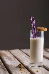  Milk glass with straws and cookie on table against gray background, copy space © wavebreak3