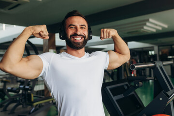 Fototapeta na wymiar Athletic man in a white shirt shows off his muscles in the gym
