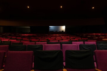 Empty dark theater with red seats separated because of the pandemic