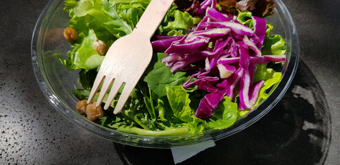 Healthy vegetable salad of fresh tomato, lettuce and red cabbage with wooden spoon and caesar salad dressing Diet menu Top view

